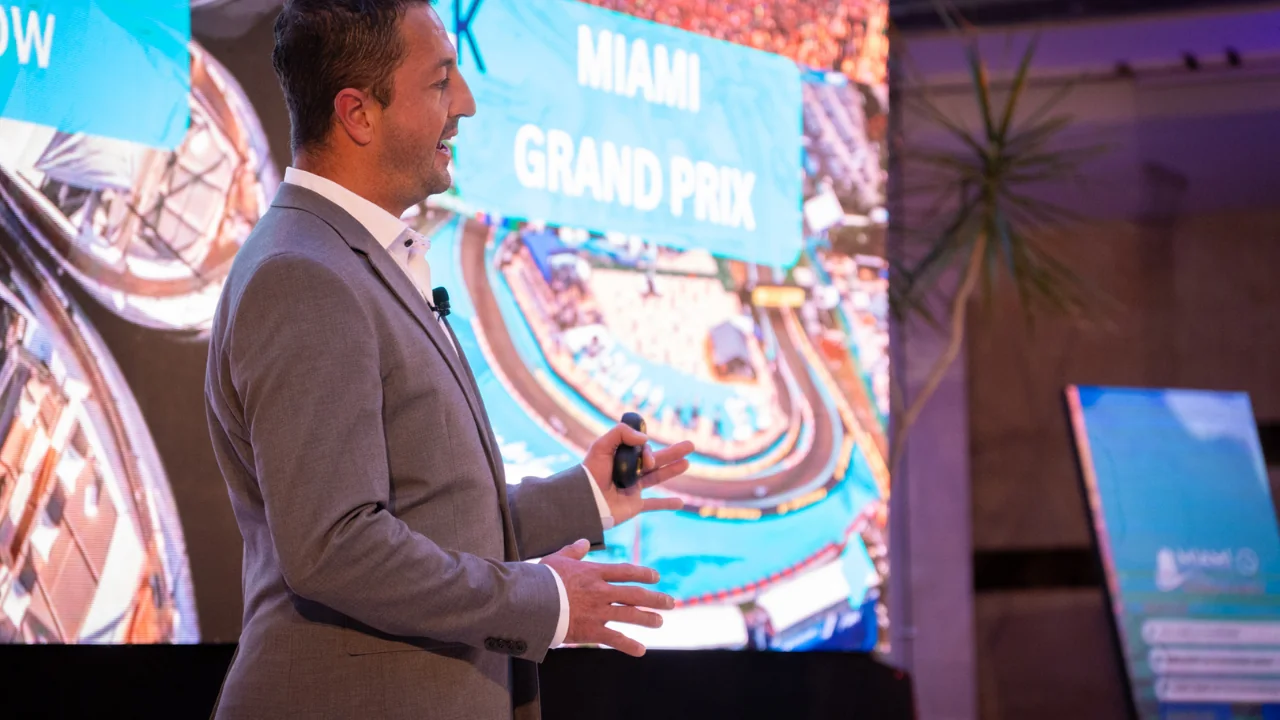 Andres Vieira of Miami Real Group presenting on stage at a Miami Grand Prix real estate investment event